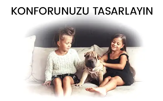 İki kız çocuk ve köpek, rahat ve konforlu ortamda güç birliği yapıyorlar, huzur ve mutluluk gözleniyor.